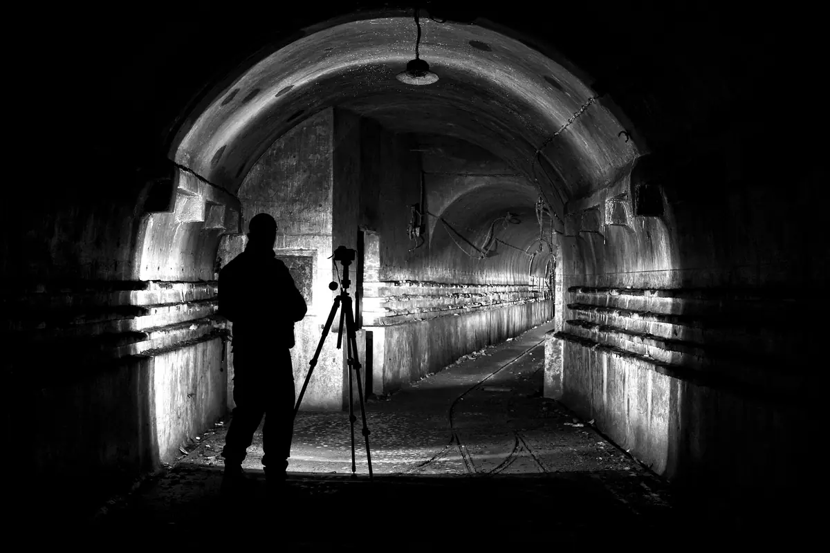 Des photographes et leur trépied en silhouette dans un tunnel éclairé