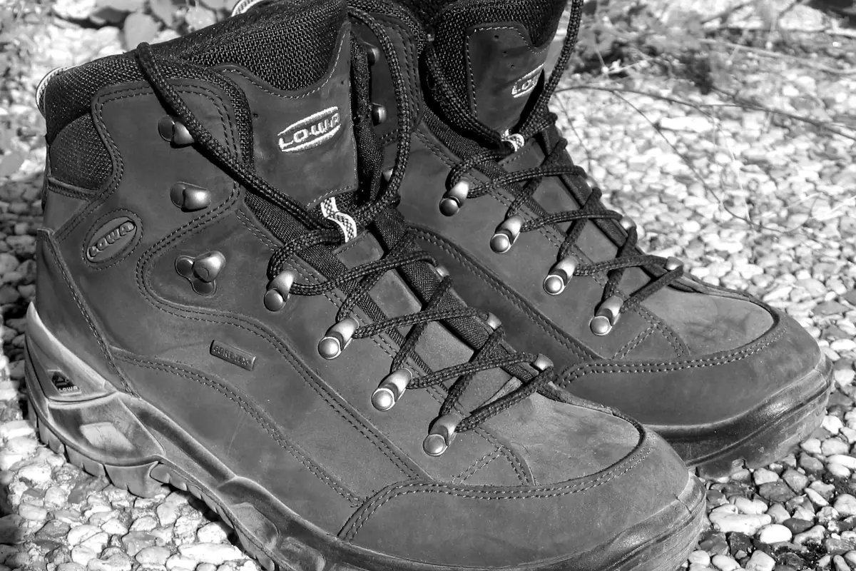 Une paire de chaussures de randonnée montantes, usées, posées sur du gravier