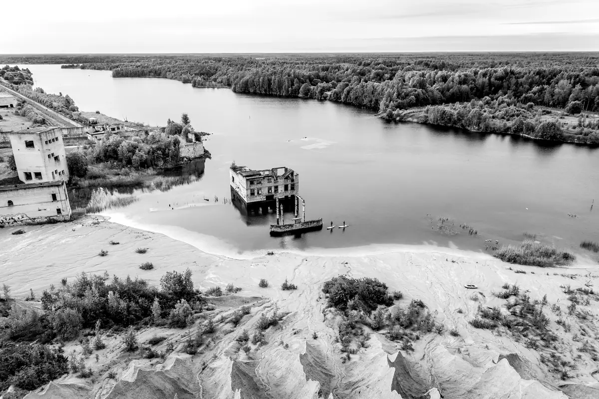 Vue de drone sur des ruines à demi englouties au bord d’un lac, au milieu d’une ancienne carrière