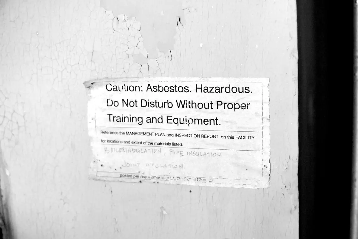 Un avertissement signalant la présence d’amiante, affiché sur un mur d’une école abandonnée