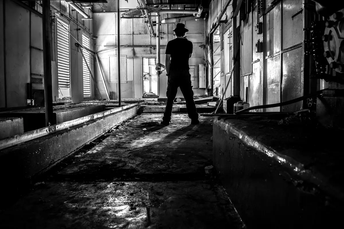 Silhouette d’un explorateur debout dans l’atelier d’une usine abandonnée